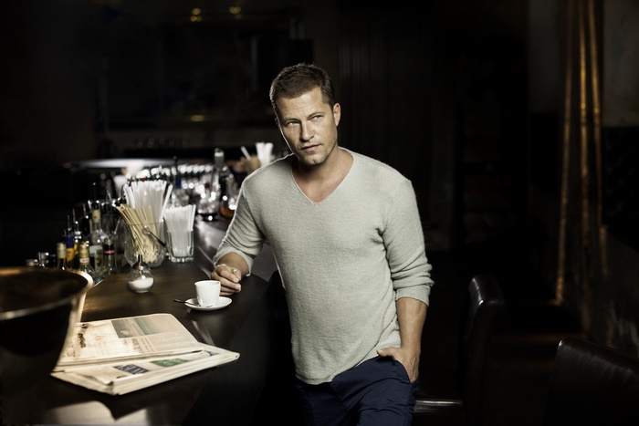 Til Schweiger at a bar with coffee and newspaper