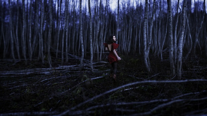 Woman in red dress in dark forest