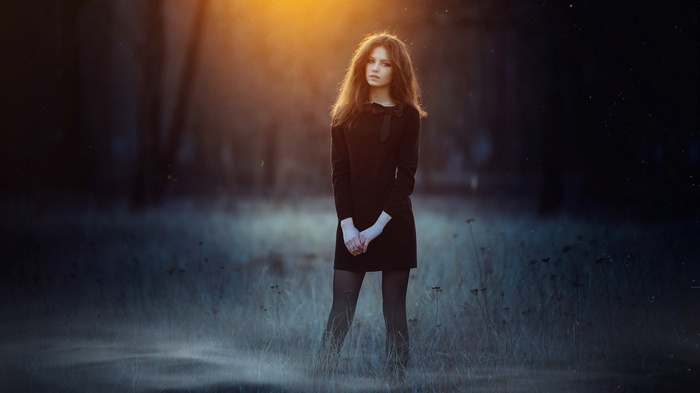 Young woman in black dress standing in a field