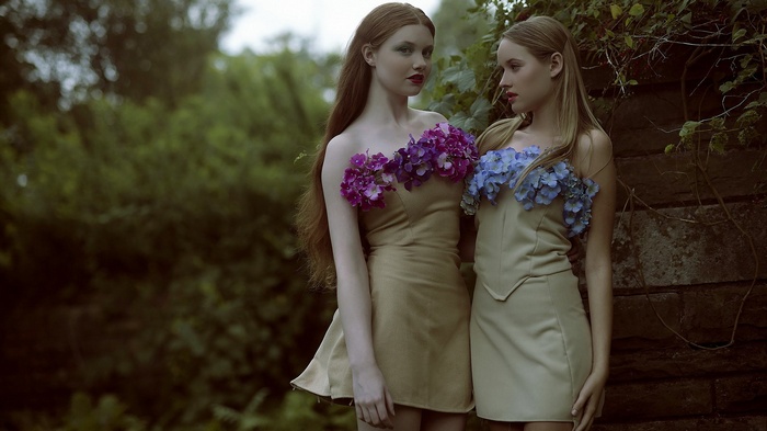 Two young women in floral dresses in a garden