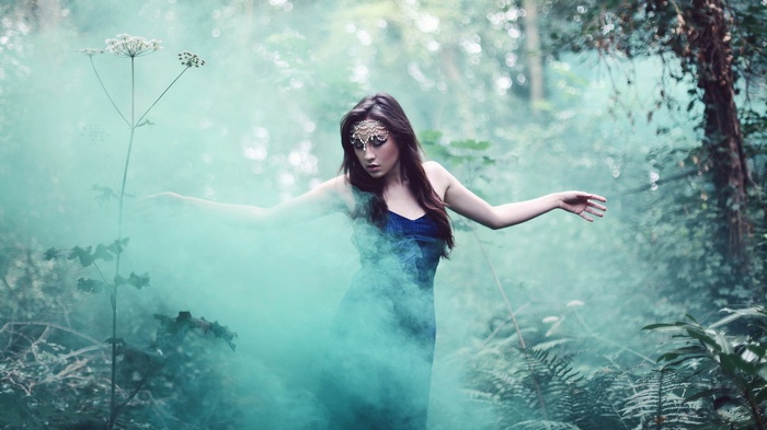 Woman in blue dress with teal smoke in forest