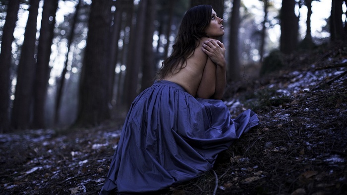 Woman in blue skirt in a dark forest