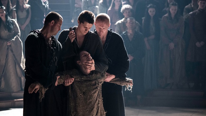 Four men restraining a person in a crowd