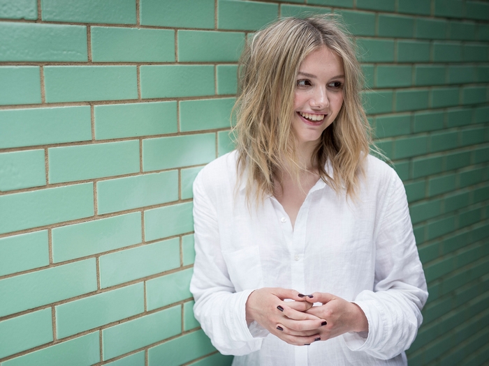 Hannah Murray against a green brick wall