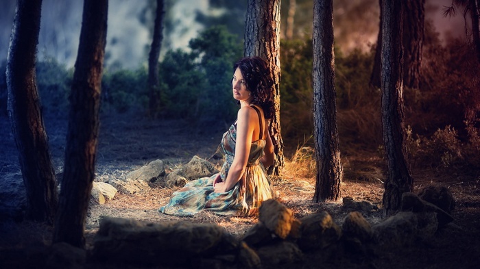 Woman in a dress sitting in a forest