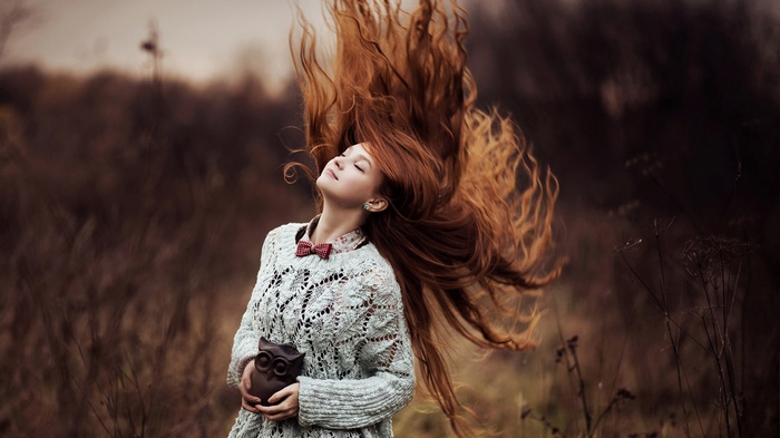 Woman with long red hair holding an owl figurine