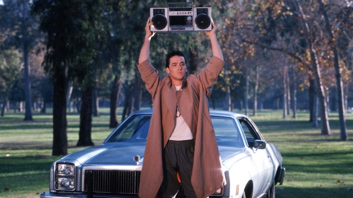 John Cusack holding a boombox in front of a car