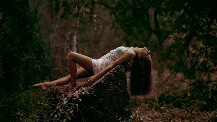 Woman lying on a rock in a forest