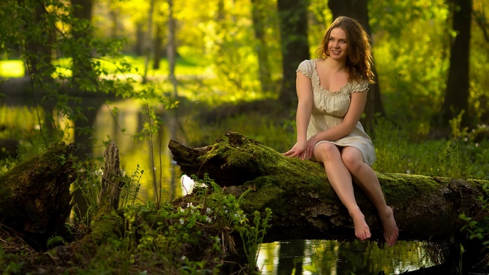 Woman sitting on a mossy log in a forest