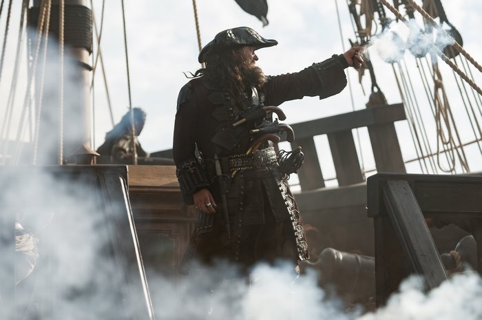 Ray Stevenson as Blackbeard firing a pistol on a ship