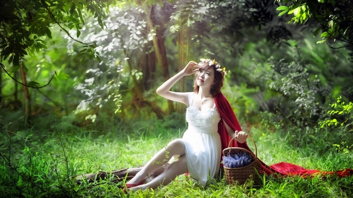 Woman in white dress with red cape in forest