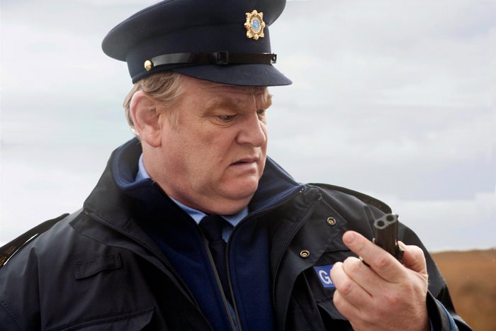 Brendan Gleeson as a police officer holding a gun