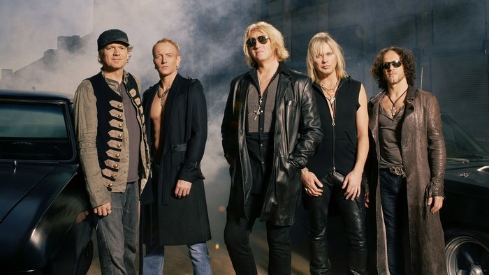 Def Leppard band members posing with cars