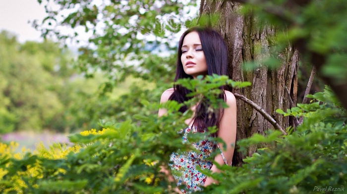 Young woman leaning against a tree in a forest