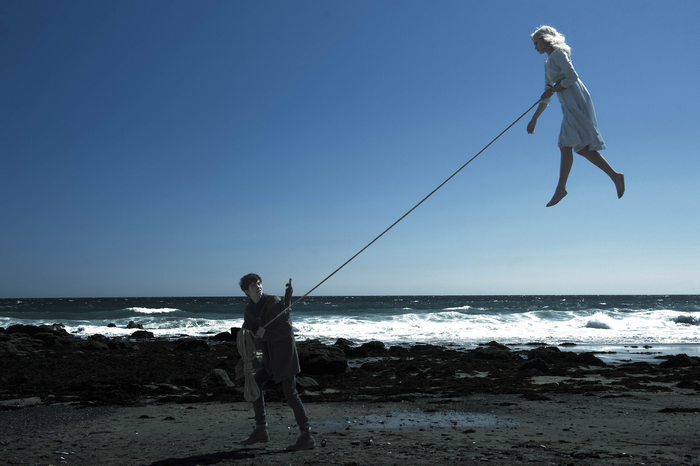 Ella Purnell suspended by rope over beach