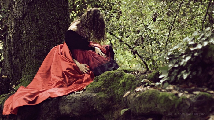 Woman in red dress sitting by a tree