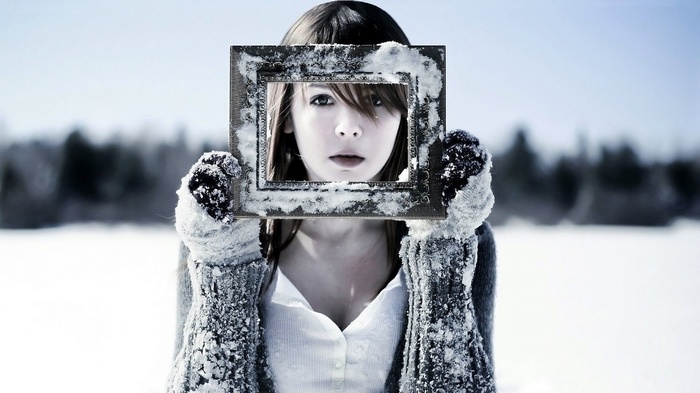 Girl holding a snow-covered frame in a winter landscape