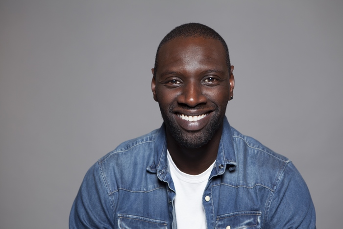 Omar Sy smiling in a denim shirt