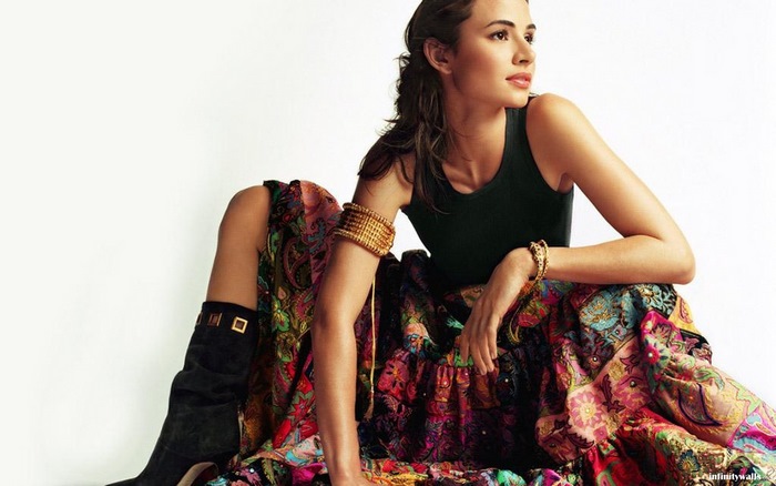 Mía Maestro sitting in a colorful skirt and black top