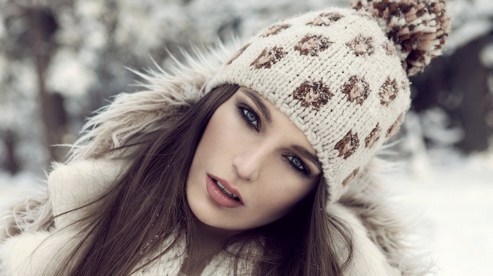 Woman in a knitted hat and fur coat in the snow