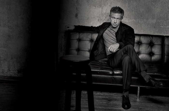 Vincent Cassel sitting on a leather couch