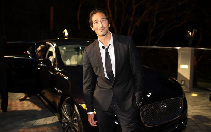 Adrien Brody standing next to a Jaguar car