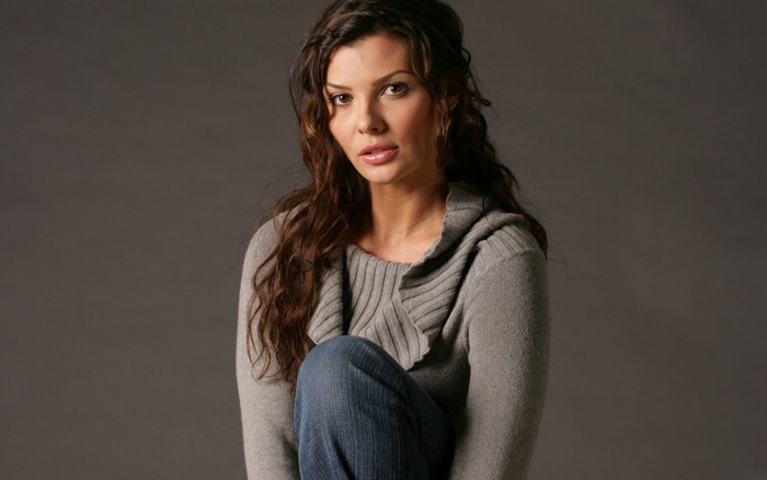 Ali Landry posing in a grey sweater and jeans