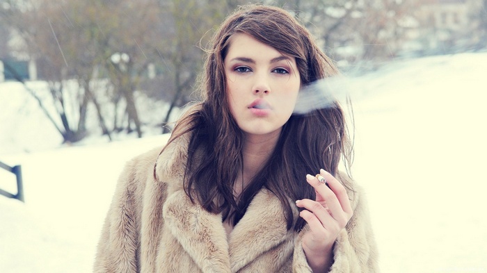 Woman in fur coat smoking in snow
