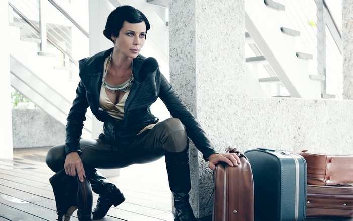Catherine Bell in futuristic attire with luggage