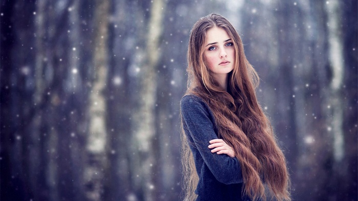 Young woman with long hair in a snowy forest