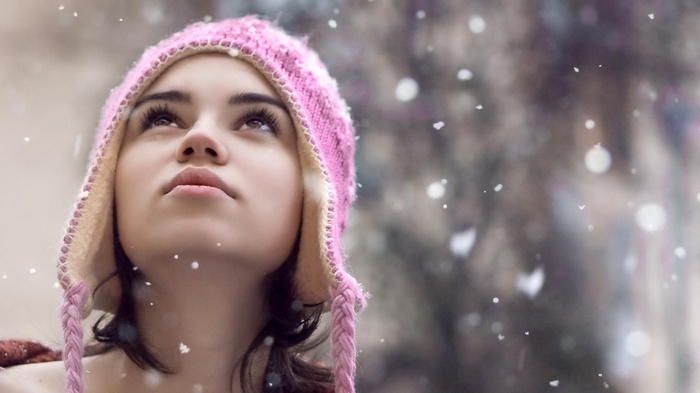 Girl in pink hat looking up at snow