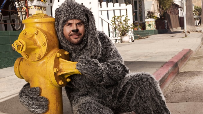 Jason Gann in a dog costume hugging a fire hydrant