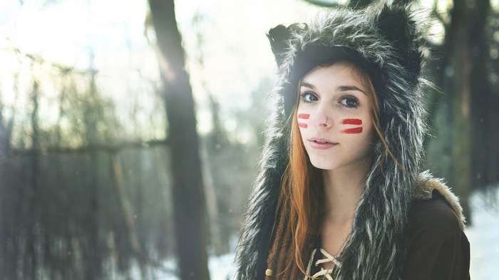 Woman with face paint and fur hood in snowy forest