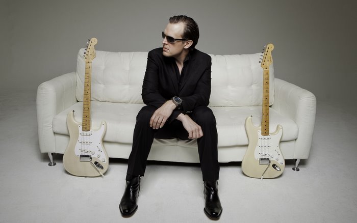 Joe Bonamassa sitting on a couch with guitars