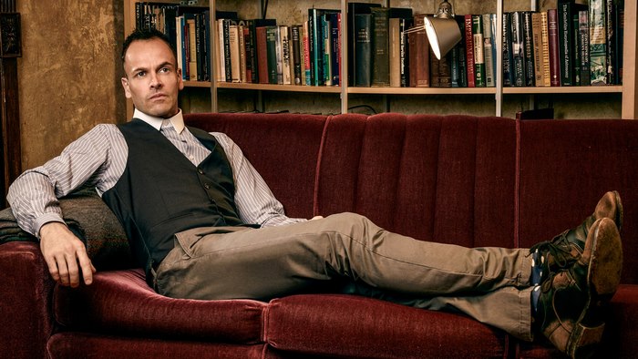 Jonny Lee Miller sitting on a couch
