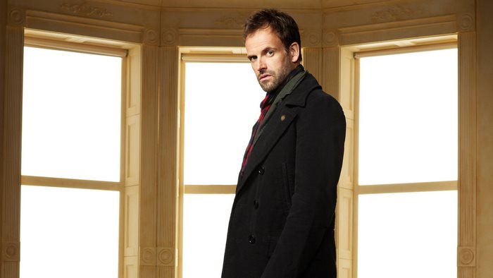 Jonny Lee Miller in a dark coat
