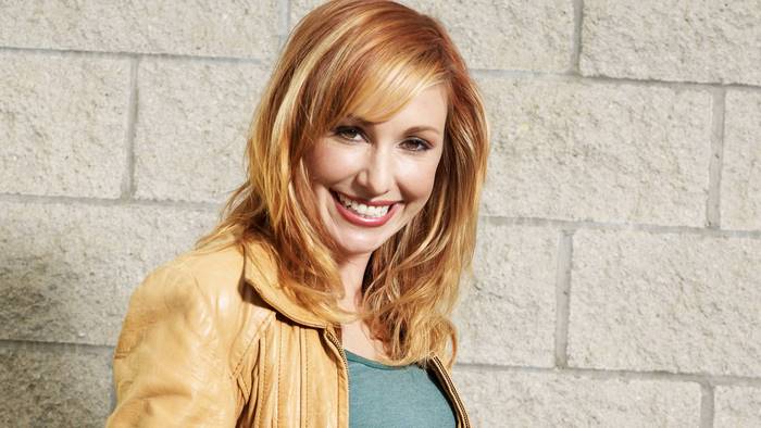 Kari Byron smiling in front of a brick wall