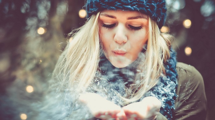 Woman blowing snow in winter