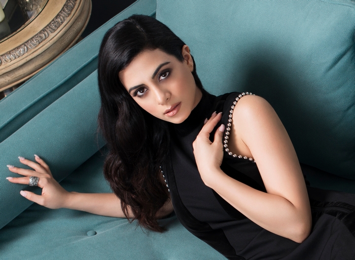 Emeraude Toubia on a teal couch