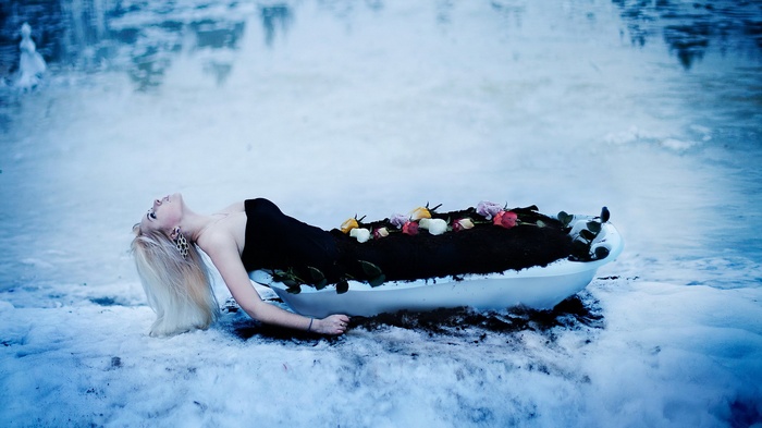 Woman lying in a bathtub filled with soil and flowers