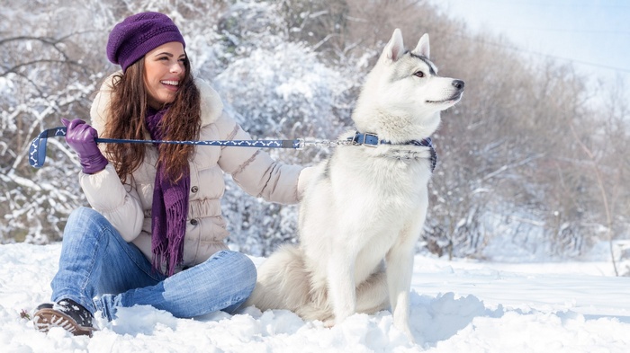 Woman in winter clothes with husky dog in snow