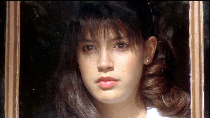 Phoebe Cates looking through a window