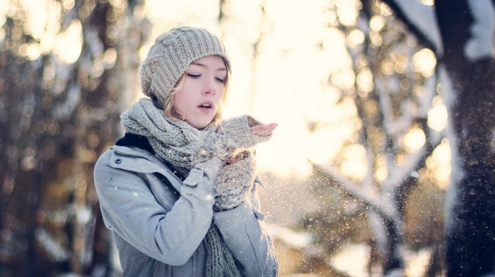 Girl blowing snow in a winter forest