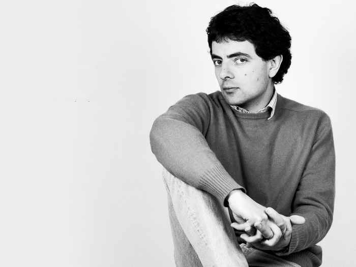 Rowan Atkinson sitting and looking to the side