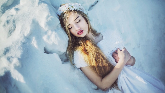 Woman with flower crown lying in snow