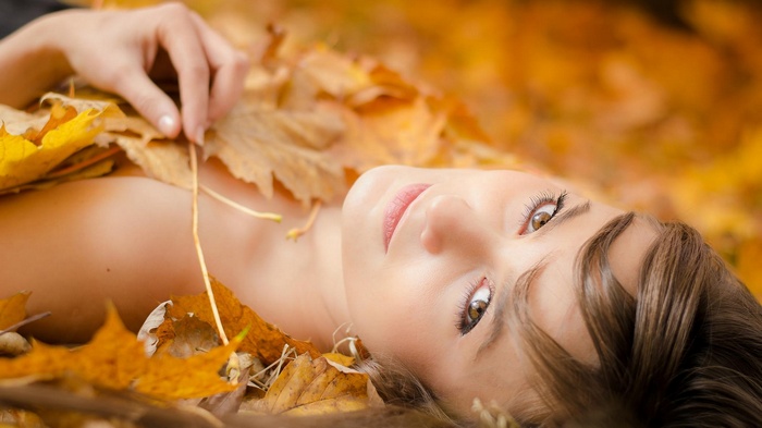 Woman lying in autumn leaves