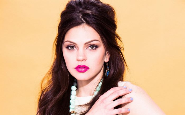 Aimee Teegarden with bright pink lipstick and blue earrings