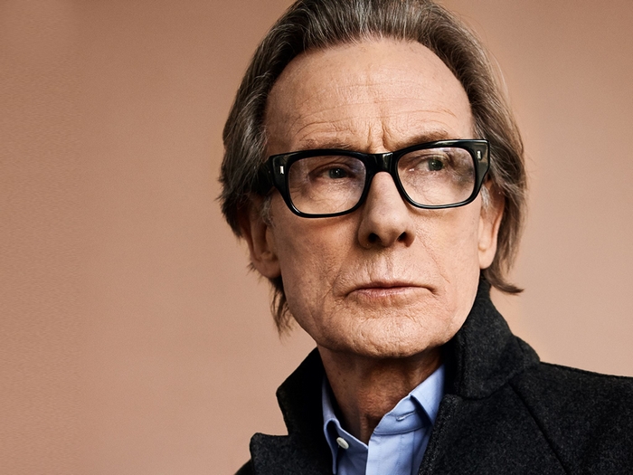 Bill Nighy wearing glasses and a coat