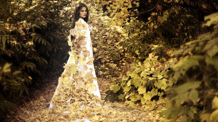 Woman in white dress covered in autumn leaves