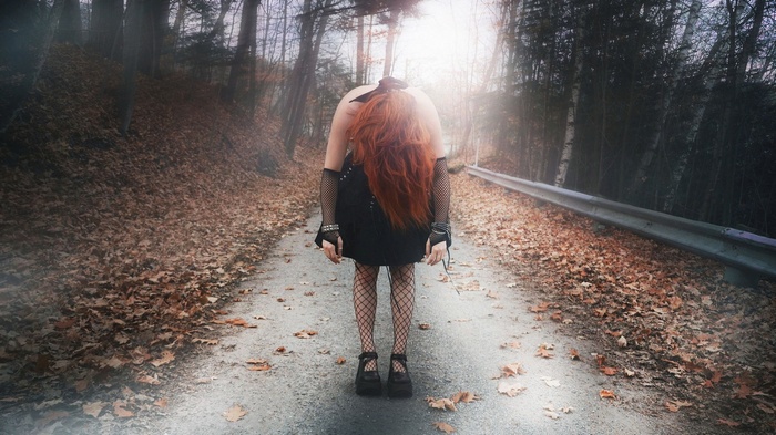 Woman with red hair bent over on a road